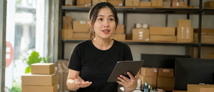 Nhân viên sales chuyển phát tư vấn cho chủ shop giữa kho hàng