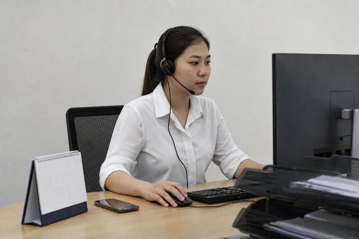 Nhân viên customer service đeo tai nghe theo dõi lô hàng cho khách